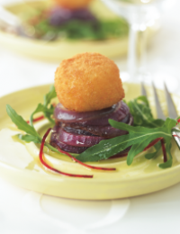 Gekarameliseerde rode ui-ringen met geitenkaaskroketje en rucola.